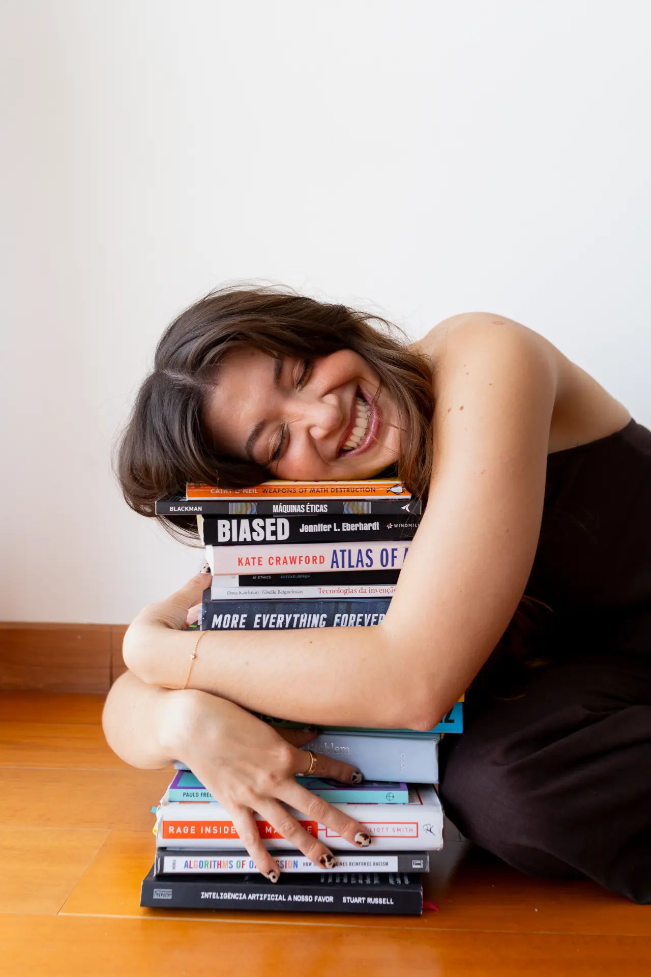 Catharina Doria resting on a stack of AI ethics books, smiling