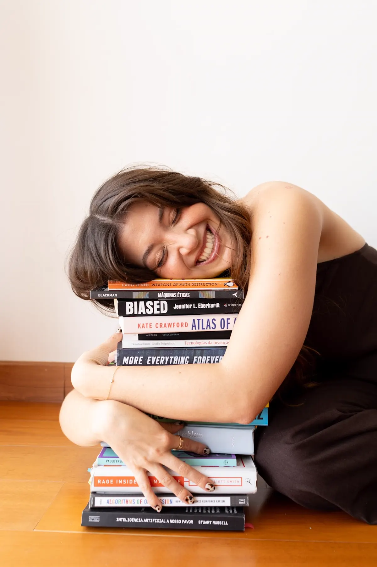 Catharina Doria resting on a stack of AI ethics books, smiling