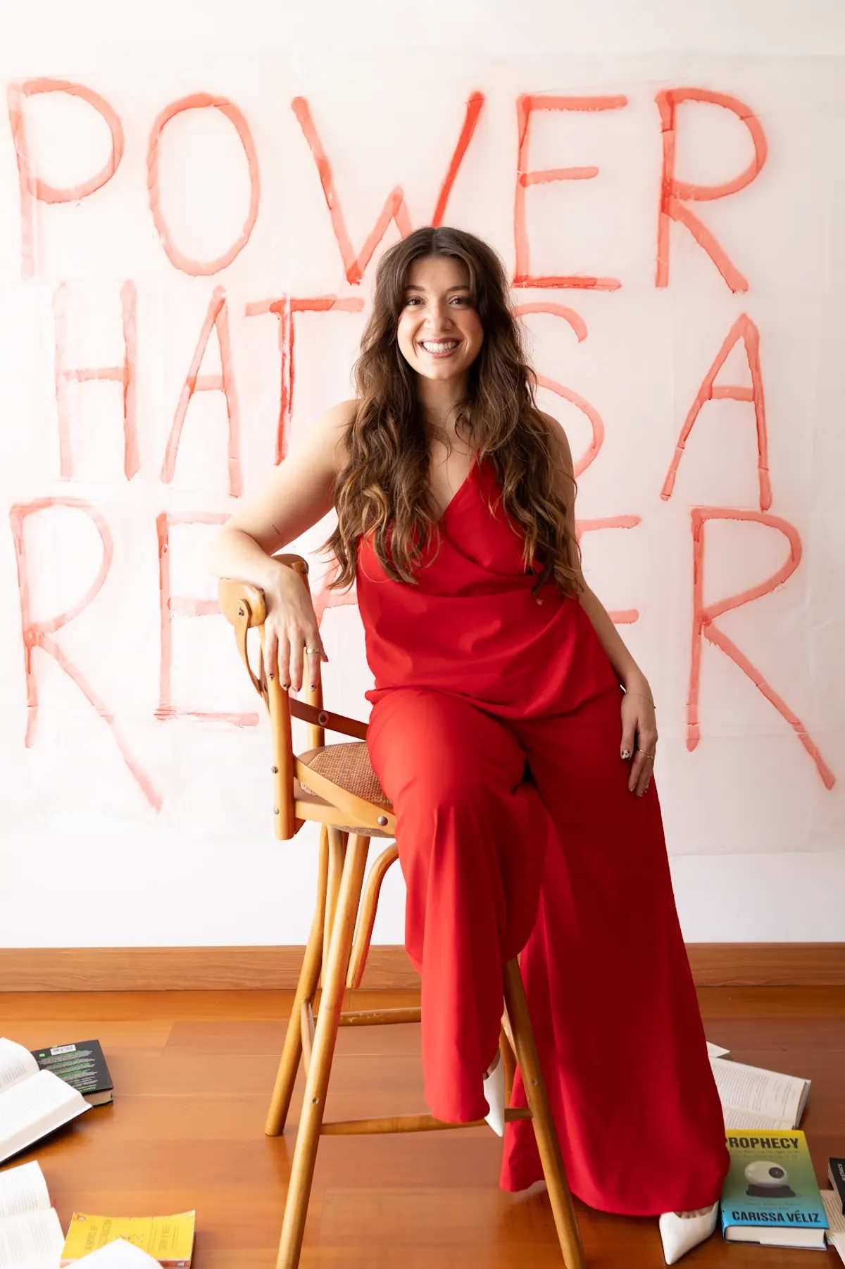 Catharina Doria in a red suit in front of a hand-painted Power Hates a Reader banner